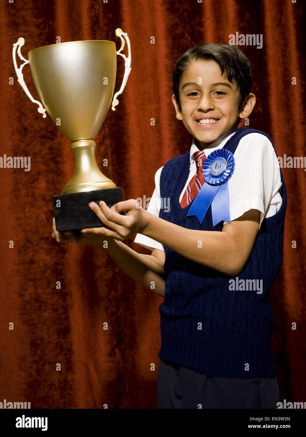 Ragazzo con nastro blu e cup trofeo sorridente Foto Stock