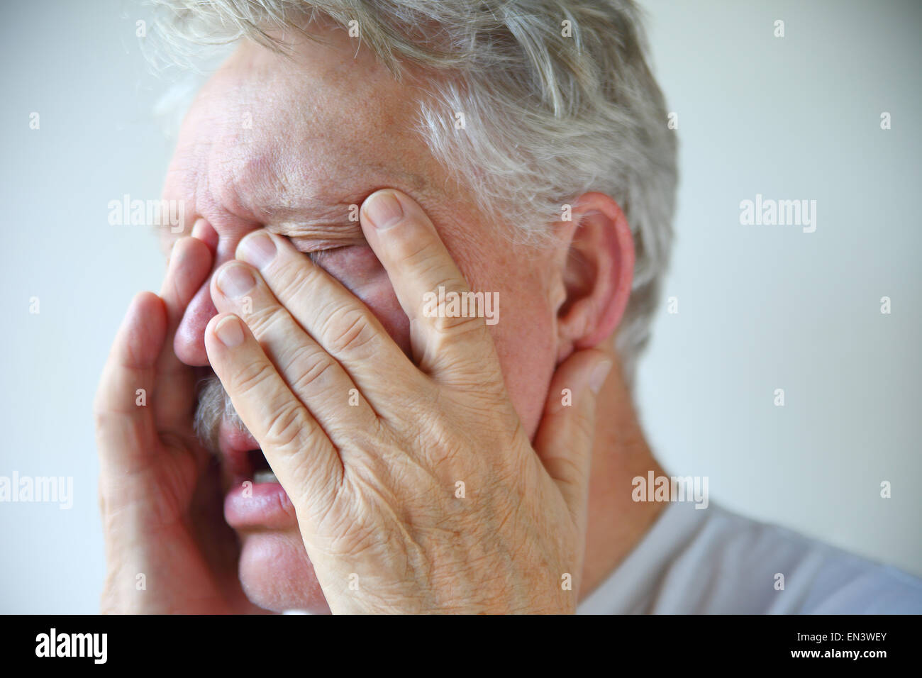Un anziano uomo sperimenta naso chiuso, ostruzione dei seni e mal di testa di una cattiva influenza o freddo Foto Stock