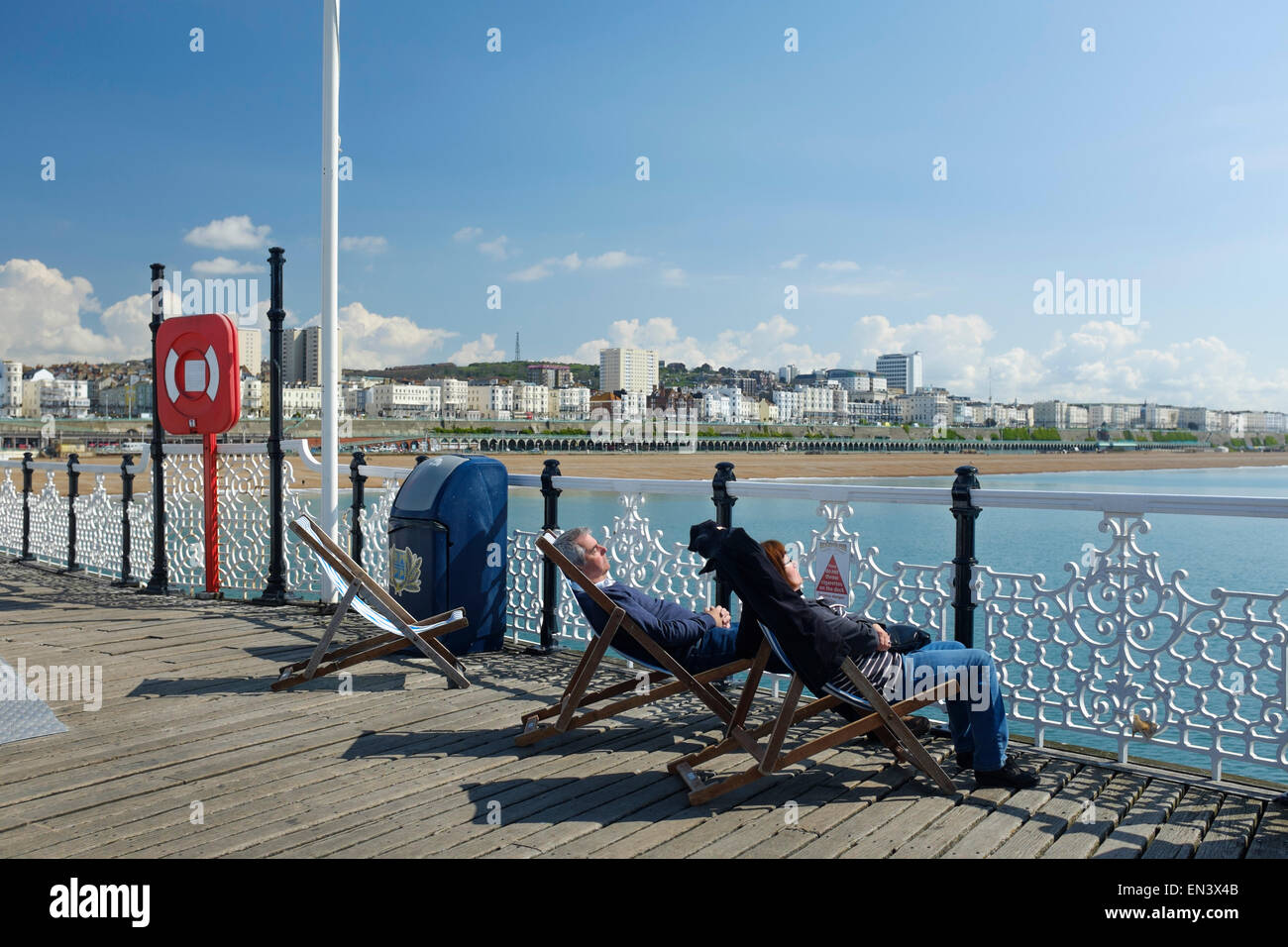 Una coppia di mezza età addormentato sulle sedie a sdraio sul molo di Brighton. Brighton, East Sussex, England, Regno Unito Foto Stock