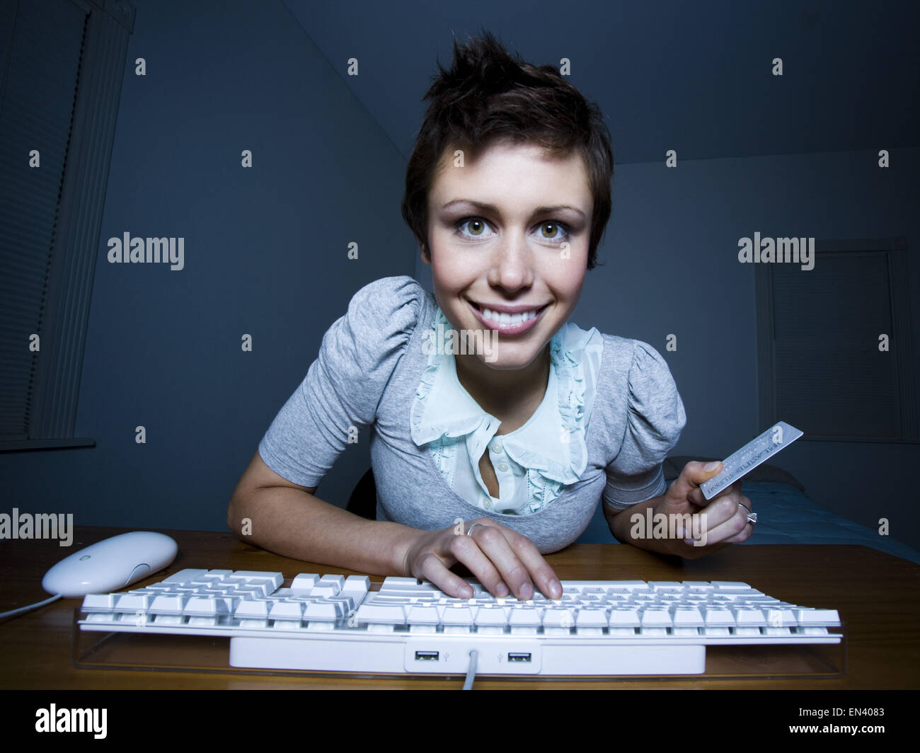 Donna seduta a tastiera con carta di credito Foto Stock