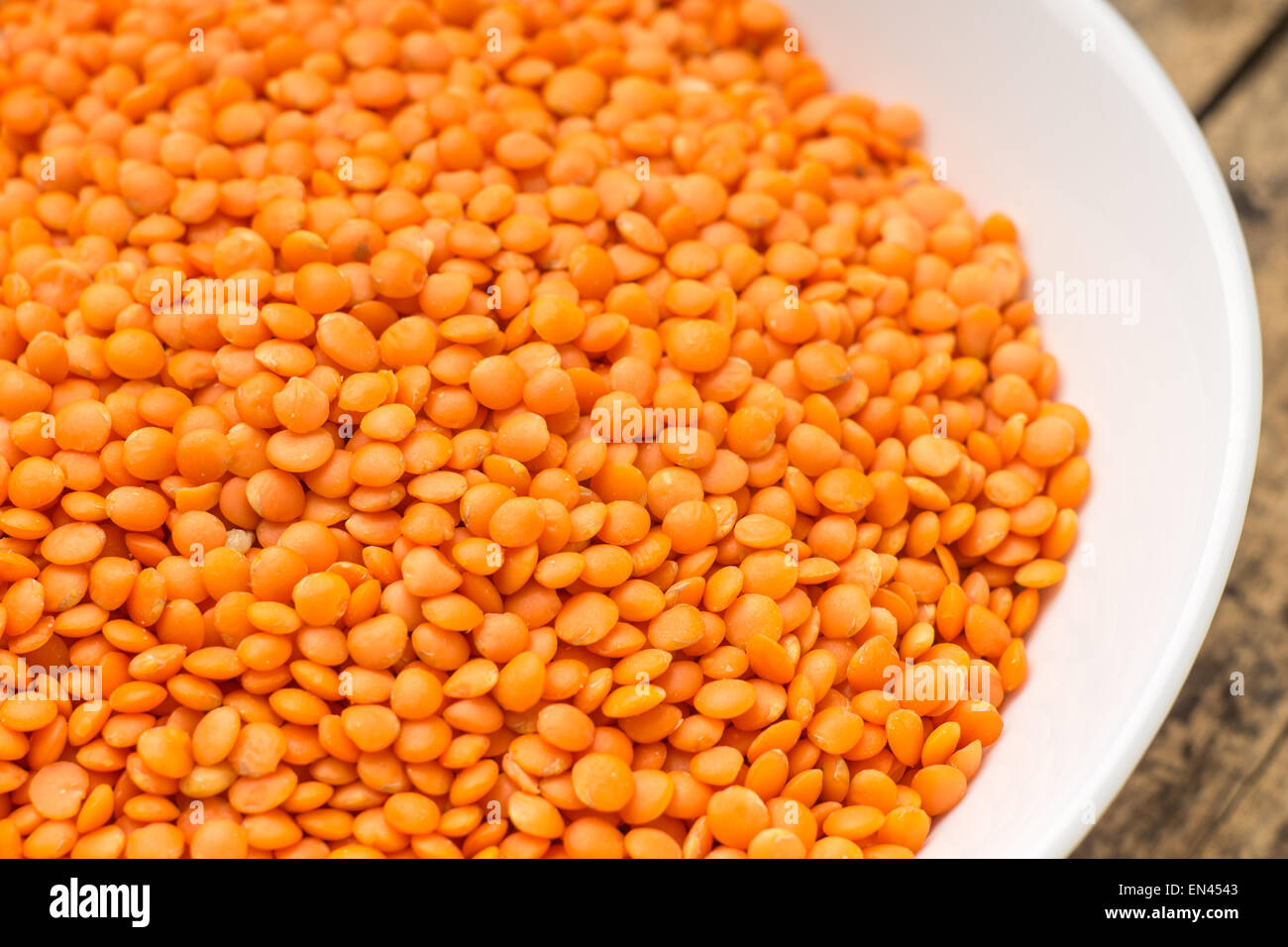 Raw lenticchia arancione in bianco ciotola. Cibo vegetariano sfondo Foto Stock