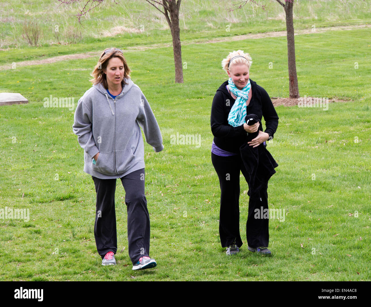 Due donne a camminare e parlare nel parco. Foto Stock