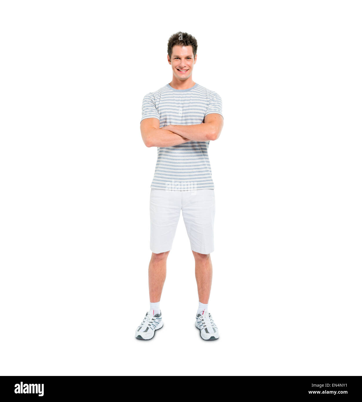 Giovane uomo fiducioso con le braccia incrociate in piedi che guarda in telecamera Foto Stock