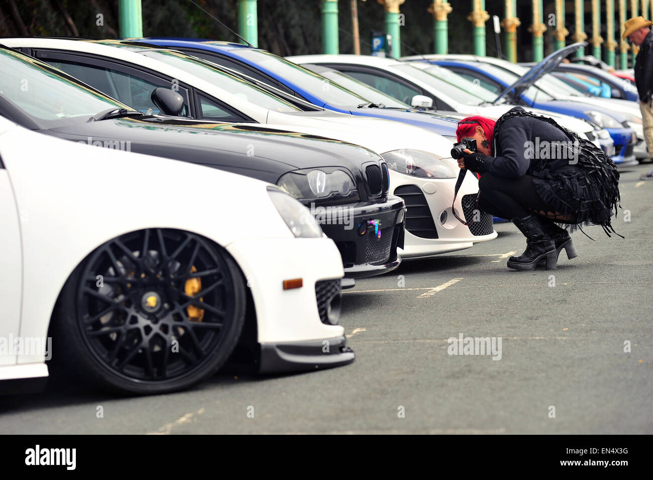 Un fotografo si accovaccia giù per fotografare una fila di automobili parcheggiate presso un Classic Car Show in Madeira Drive in Brighton. Foto Stock