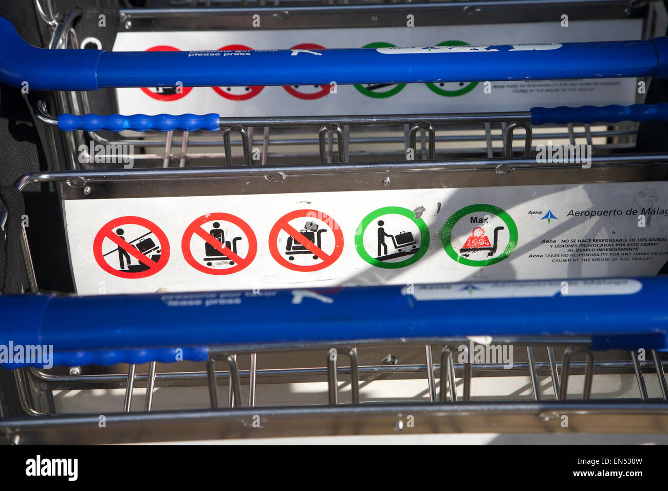 Close up della linea di una pila di carrelli portabagagli con informazioni sulle regole di utilizzo, dall'aeroporto di Malaga, Spagna Foto Stock