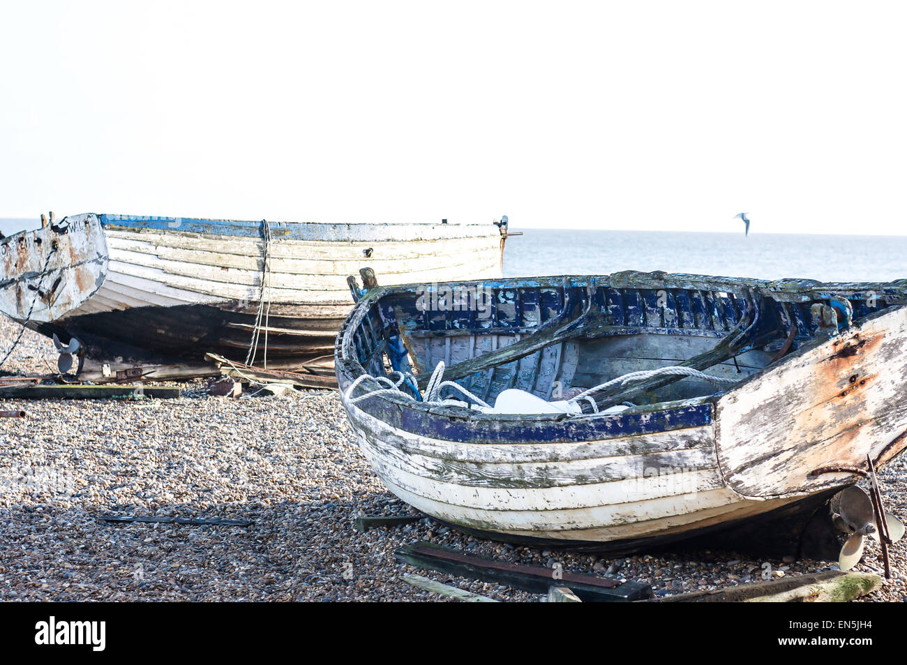 Tono pallido barche da pesca su una ghiaia (shingle) spiaggia in riva al mare. Foto Stock
