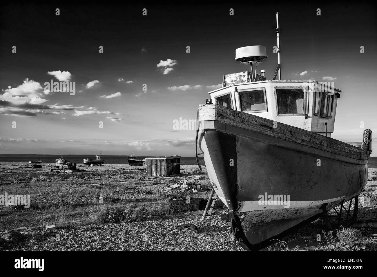 Abbandonata la pesca in barca sulla spiaggia di ciottoli paesaggio al tramonto in bianco e nero Foto Stock