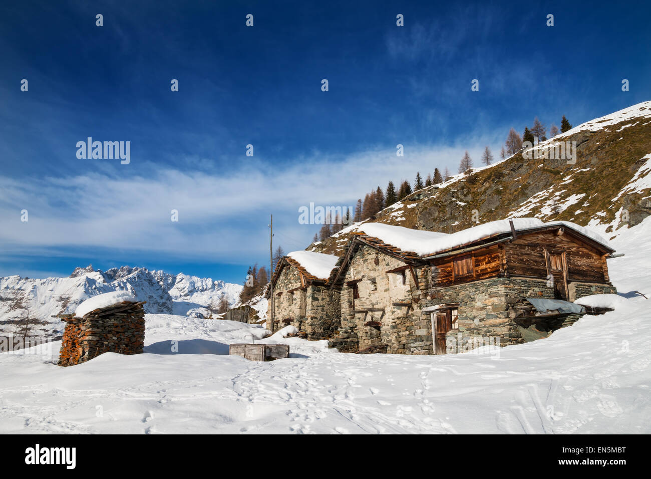 Abbandonato Chalet tipico nelle alpi italiane sotto il cielo blu con alcune nuvole bianche Foto Stock