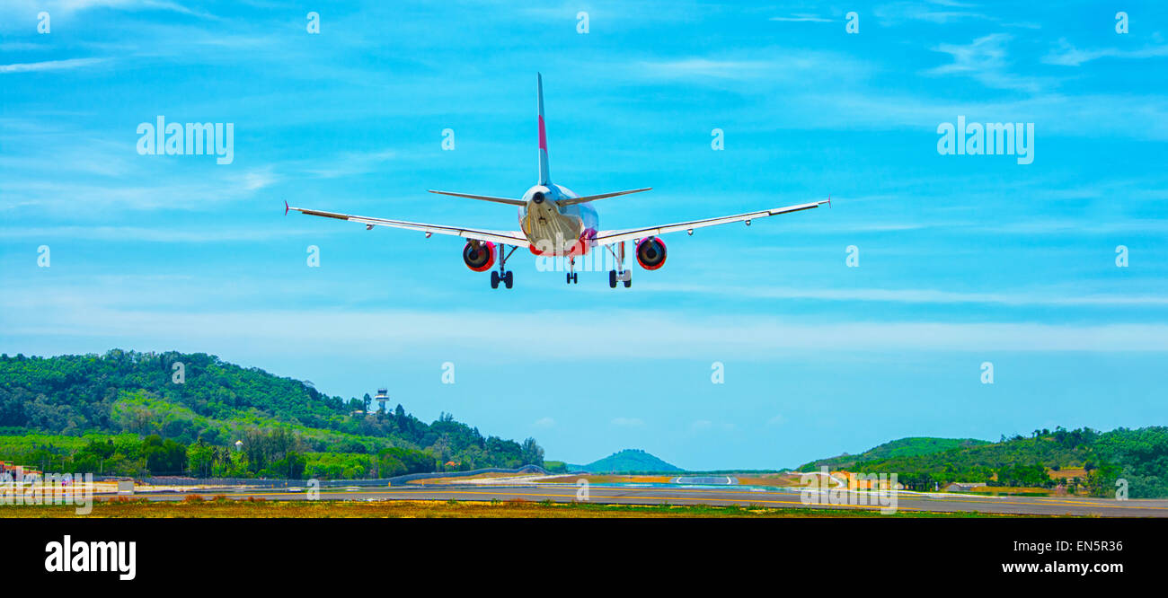 Twin-motore, aereo commerciale in arrivo per un atterraggio in un aeroporto in un ambiente tropicale, a sud-est del paese asiatico. Un luminoso cielo blu Foto Stock