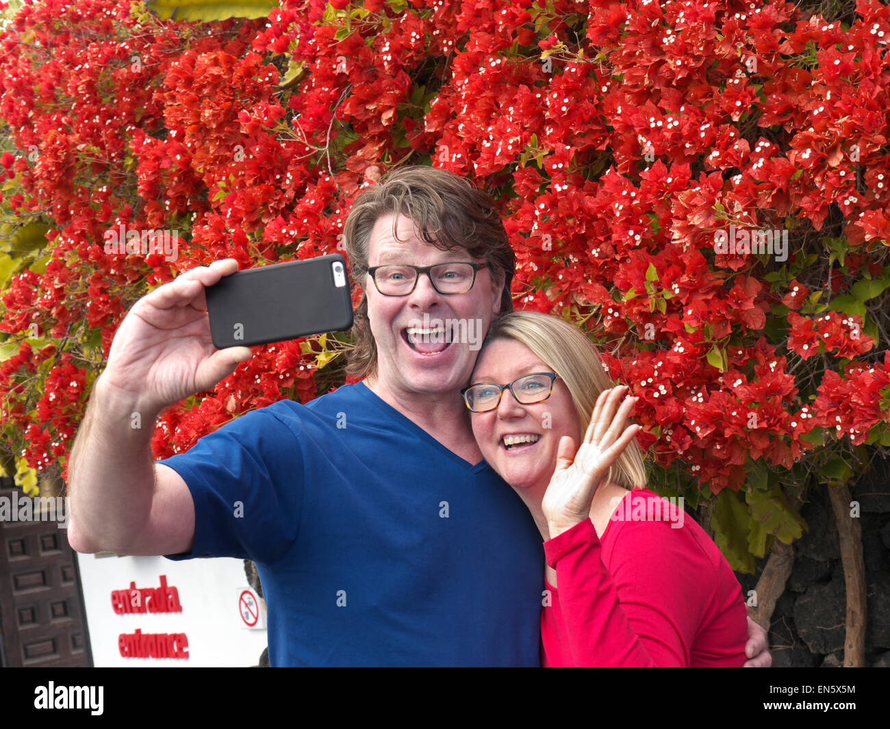 'SELFIE' coppia attraente divertirsi in vacanza prendendo un 'selfie' photo al di fuori di attrazione di vacanza sul loro iPhone 6 applicazione della fotocamera Foto Stock