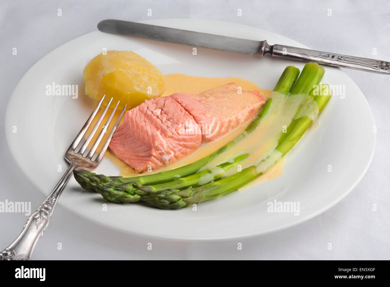 Asparagi verdi e poached salmone con salsa maltaise (variazione hollandaise) con una patata su una piastra bianca Foto Stock