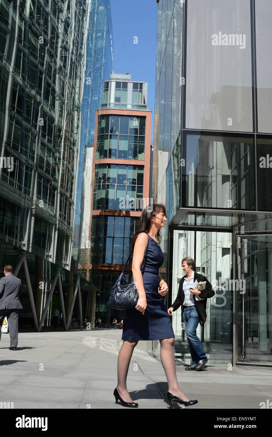 Attraente business donna a piedi nella parte anteriore di alti edifici per uffici a Londra Foto Stock