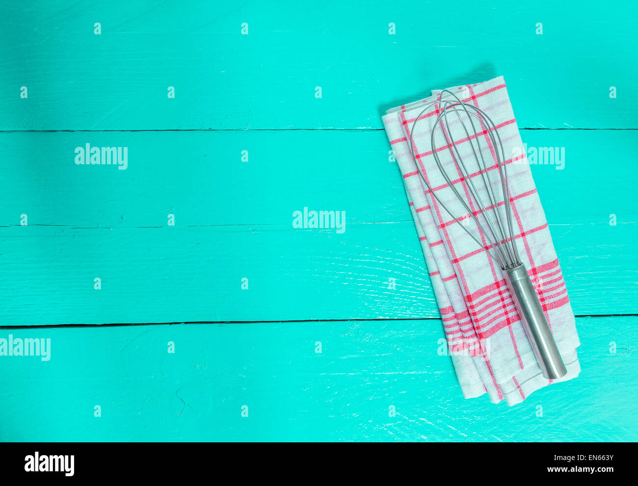 Mescolare con una frusta e tovagliolo sul turchese sullo sfondo di legno. Foto Stock