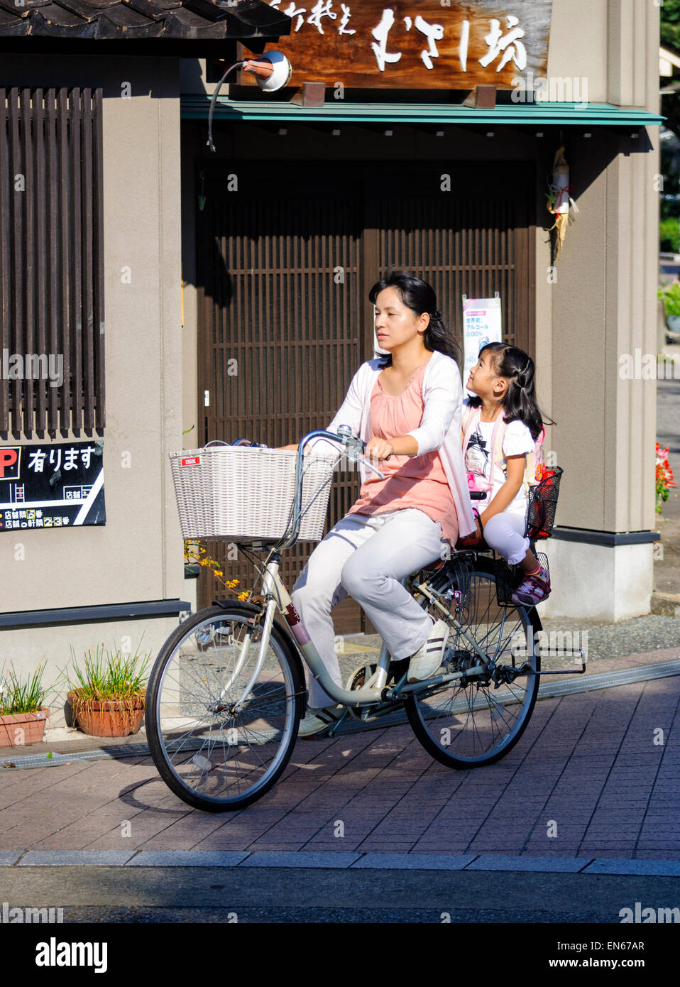 È comune vedere due persone in sella ad una bicicletta singolo in Giappone - in particolare di madri e bambini piccoli. Giapponese madre e bambino; figlia; bike. Foto Stock