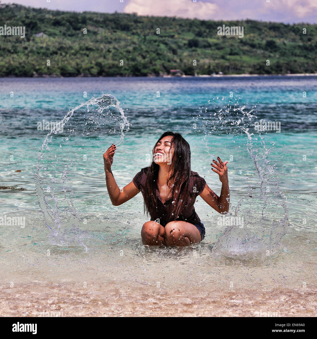Giovane donna gli spruzzi di acqua di mare nelle Filippine Foto Stock