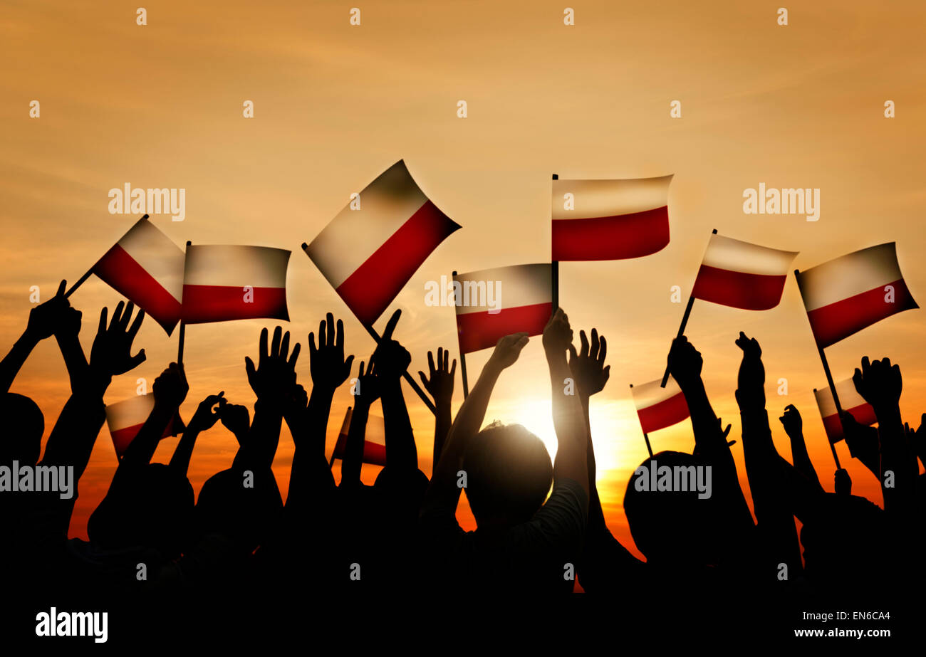 Gruppo di persone sventolando bandiere polacche nel retro illuminato Foto Stock