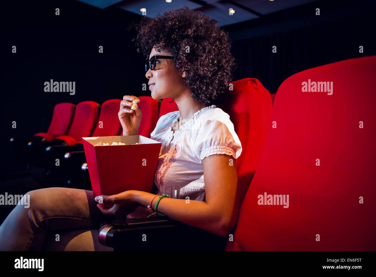 Giovane donna guardando un film 3d e mangiare pop corn Foto Stock
