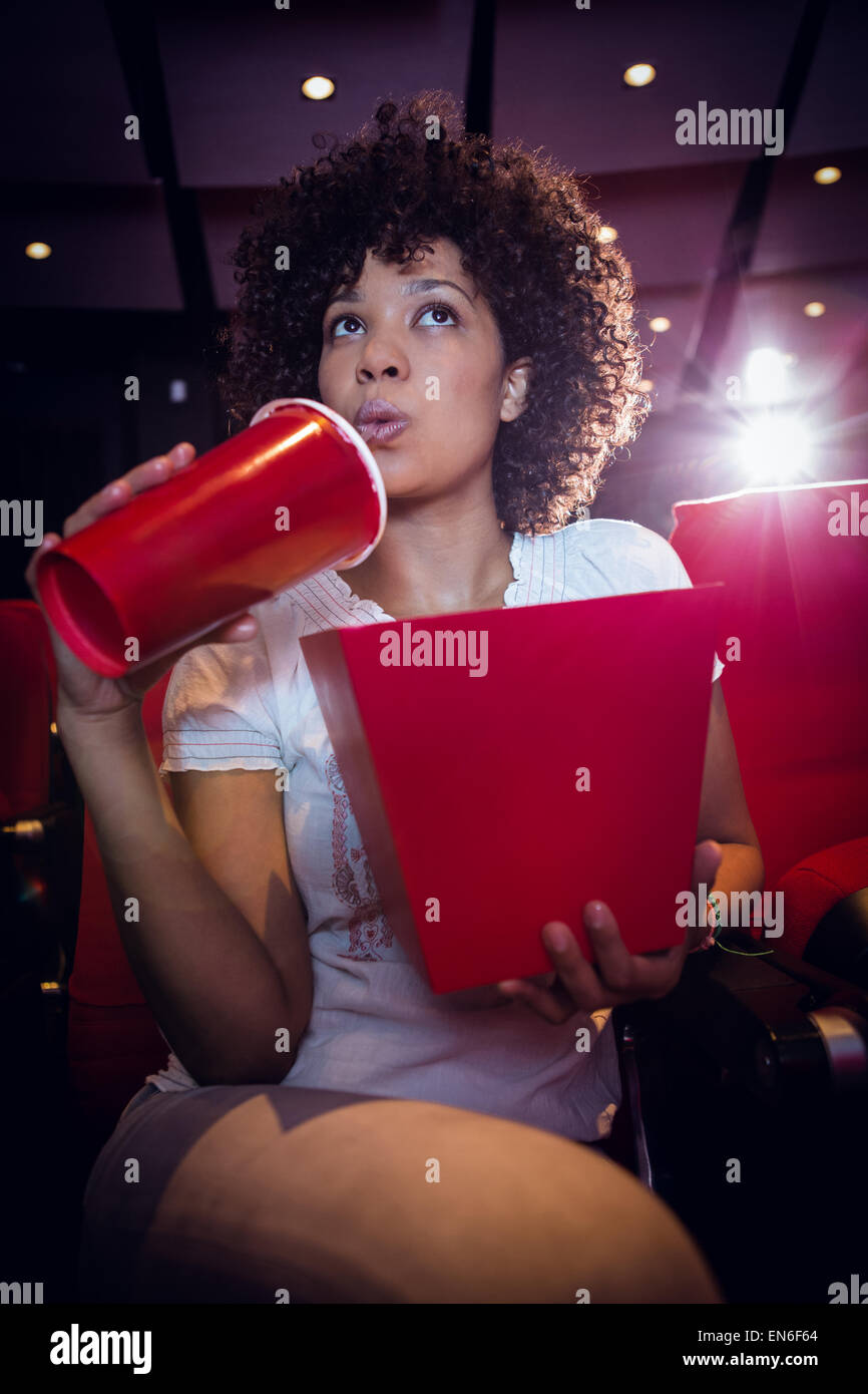 Giovane donna guardando un film e di bere una soda Foto Stock