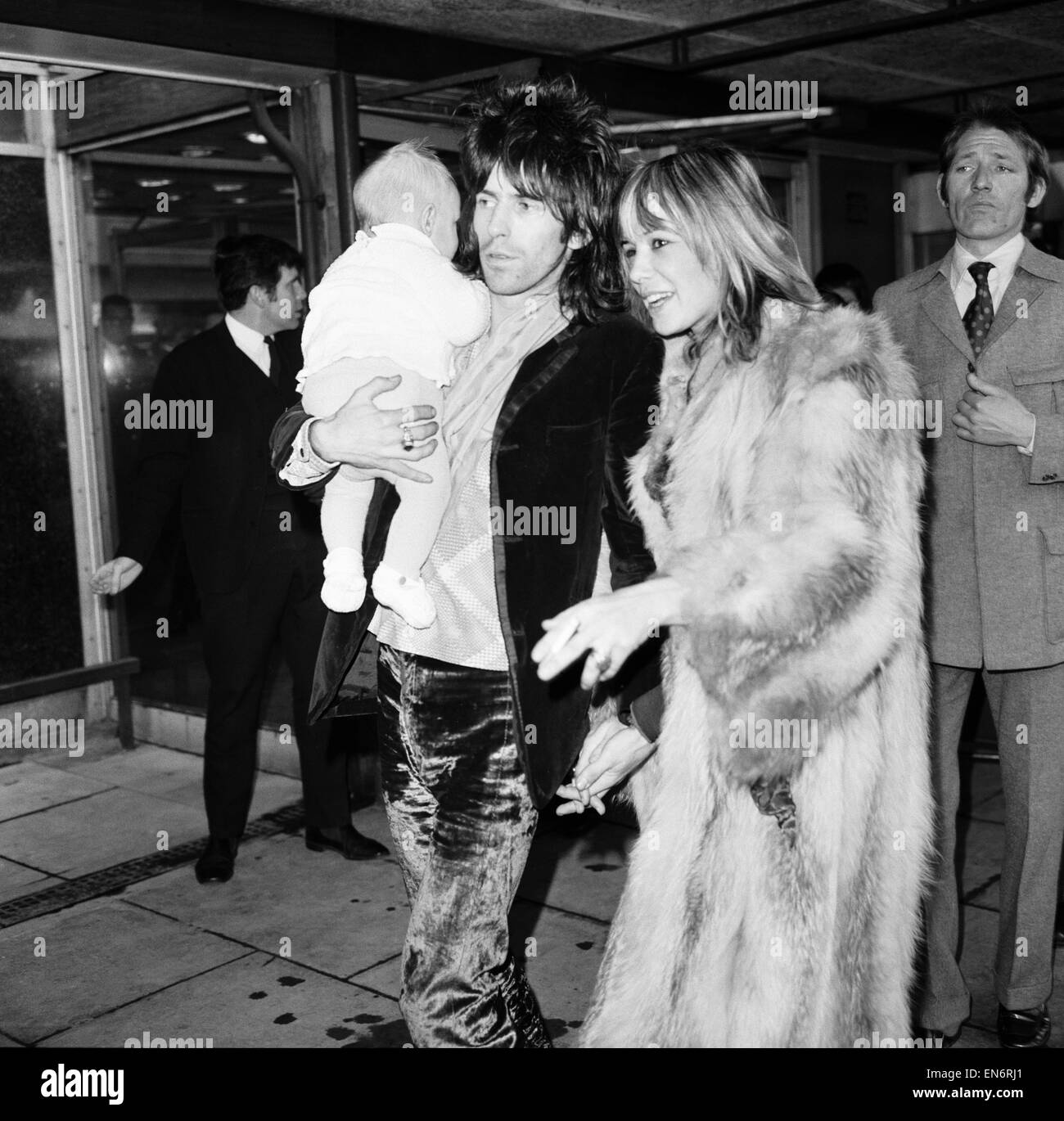 Rolling Stones chitarrista Keith Richards presso l'aeroporto di Heathrow si è riunito di Anita Pallenberg e quattro mese vecchio figlio Marlon, Dicembre 1969 Foto Stock