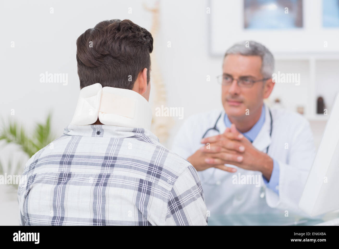 Medico guardando il paziente che indossa il rinforzo del collo Foto Stock