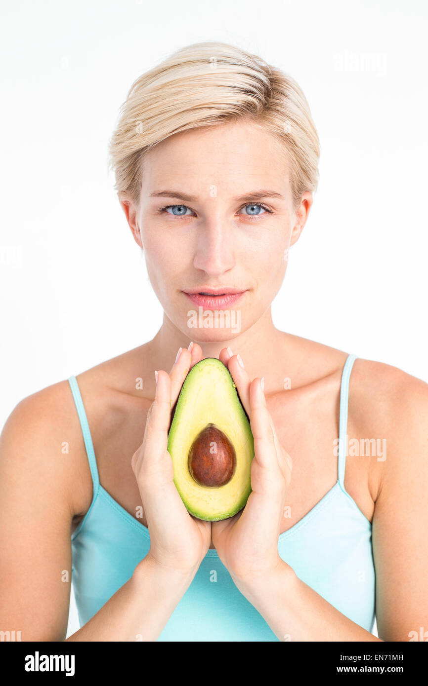 Donna attraente che mostra la metà di un avocado Foto Stock