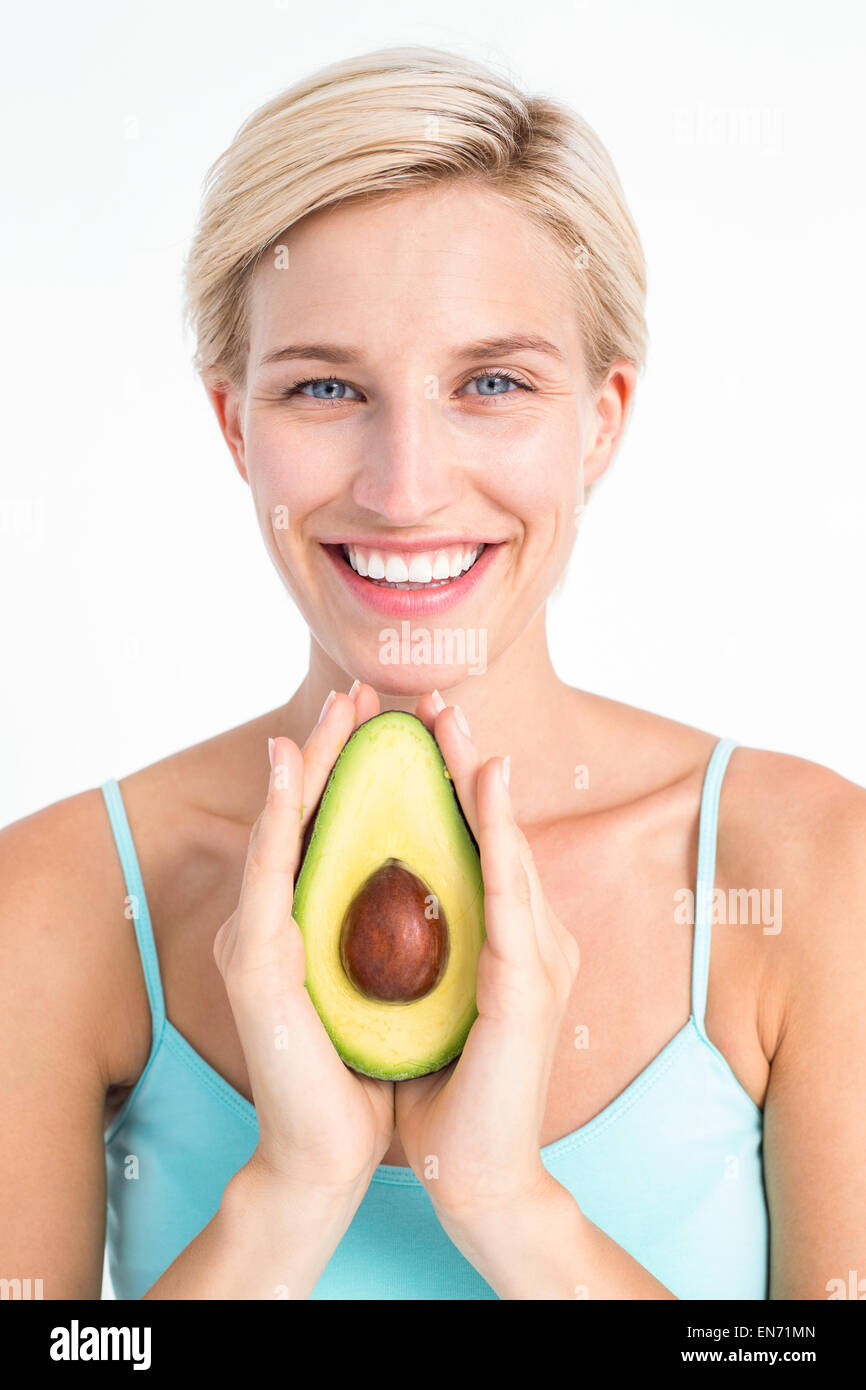 Donna attraente che mostra la metà di un avocado Foto Stock