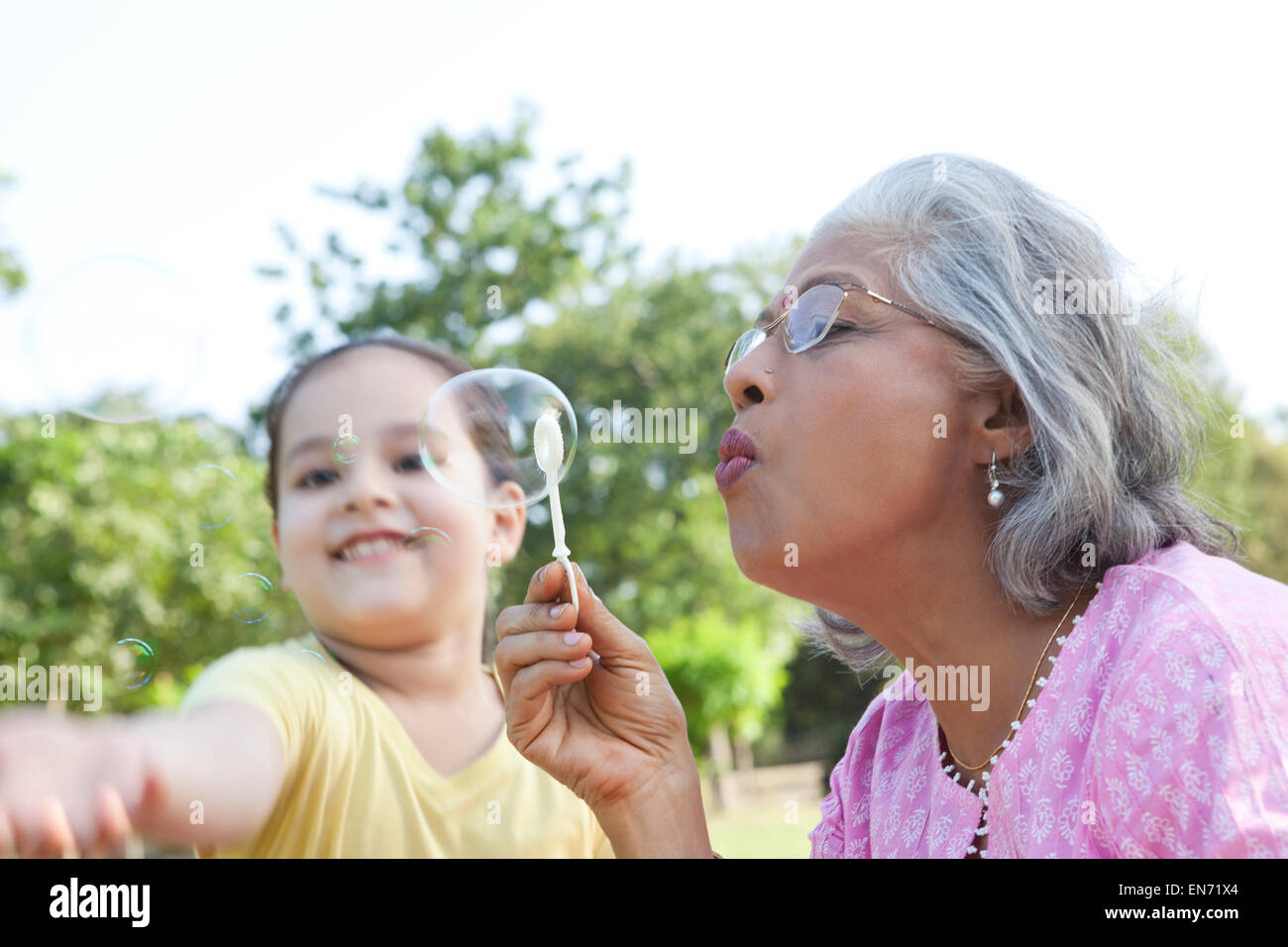 Senior donna soffiare bolle Foto Stock