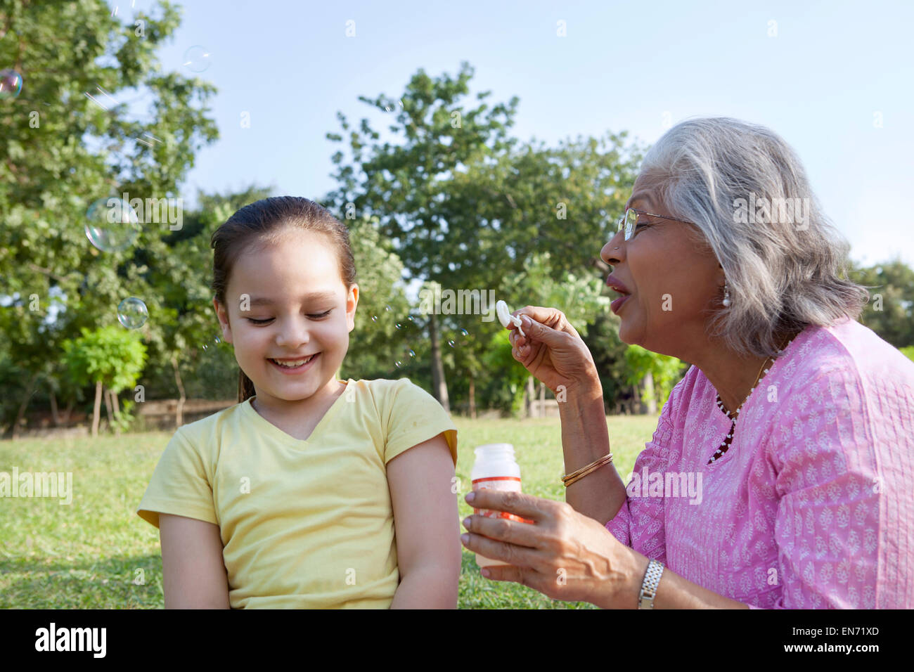 Nonna soffiare bolle al nipote Foto Stock