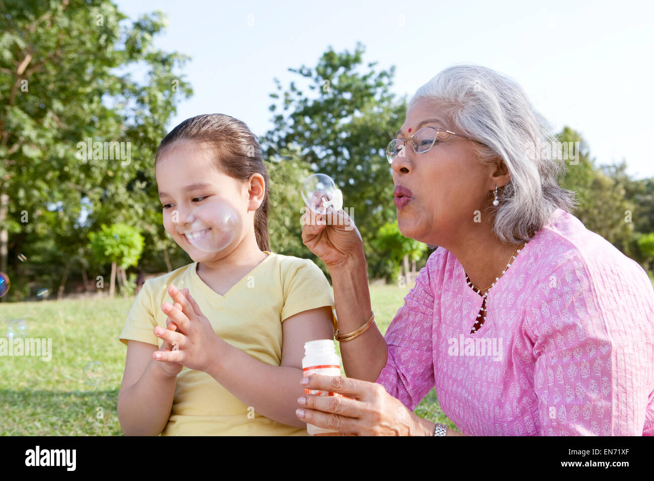 Nonna soffiare bolle per la nipote Foto Stock