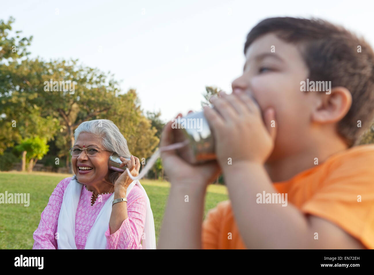 Nonna e nipote di parlare attraverso le lattine di alluminio Foto Stock