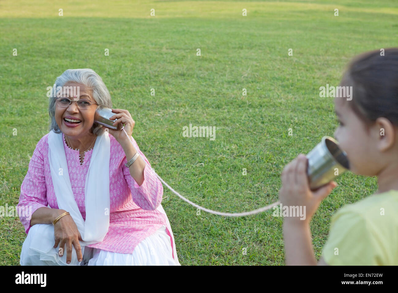 Nonna e nipote di parlare attraverso le lattine di alluminio Foto Stock