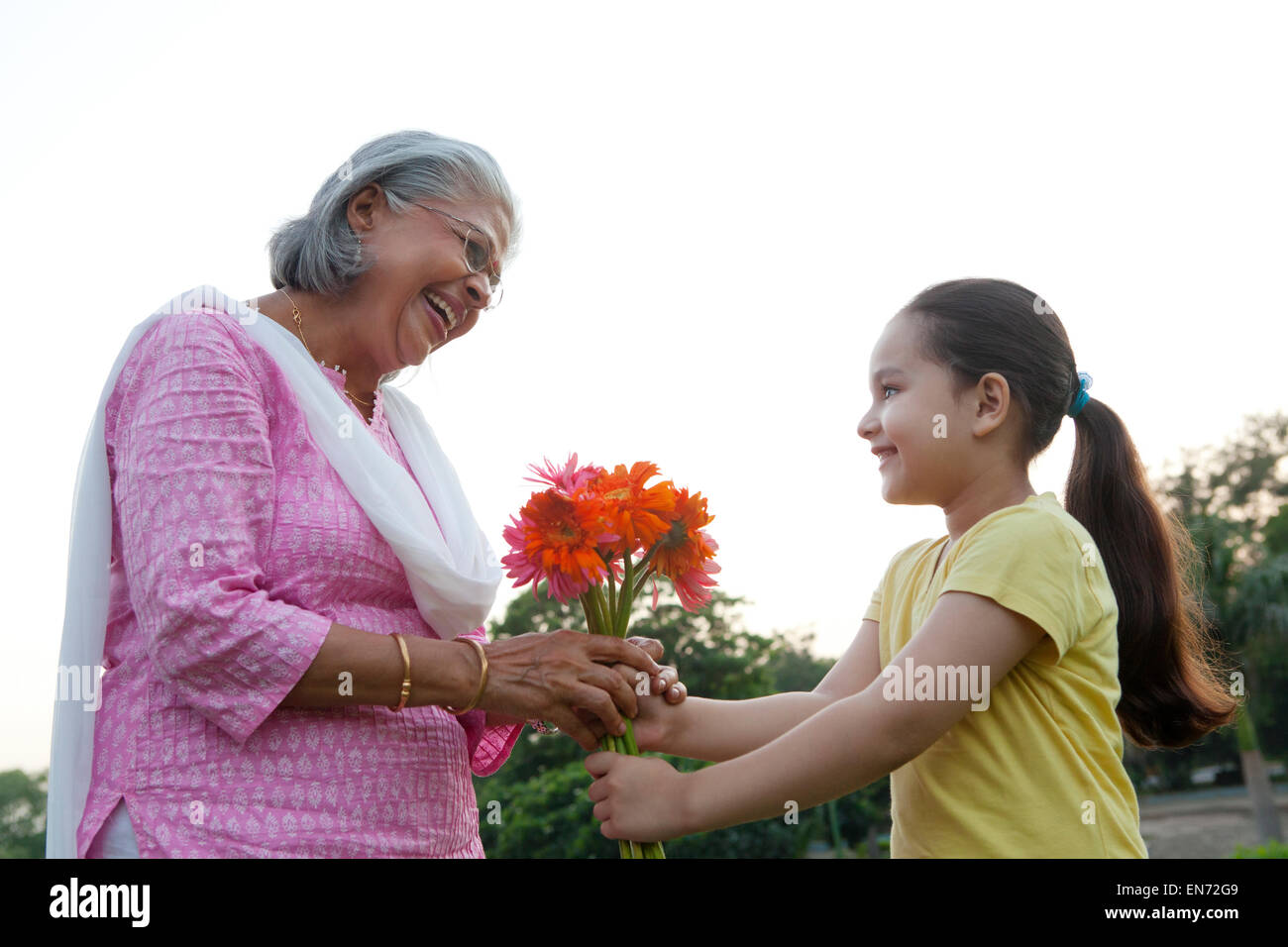 Ragazza dando la nonna fiori Foto Stock