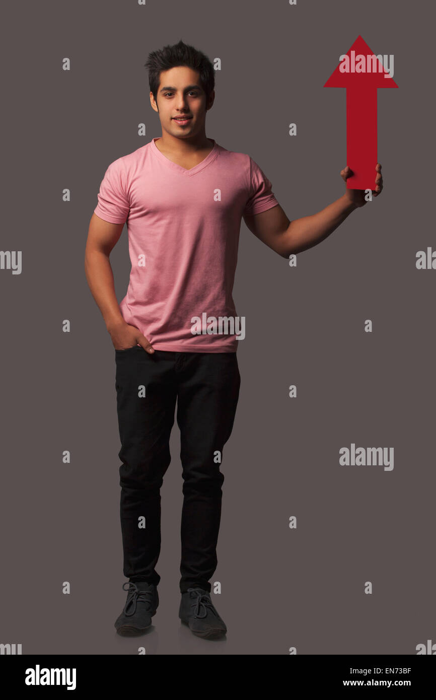 Ritratto di giovane uomo tenendo premuto segno di freccia Foto Stock
