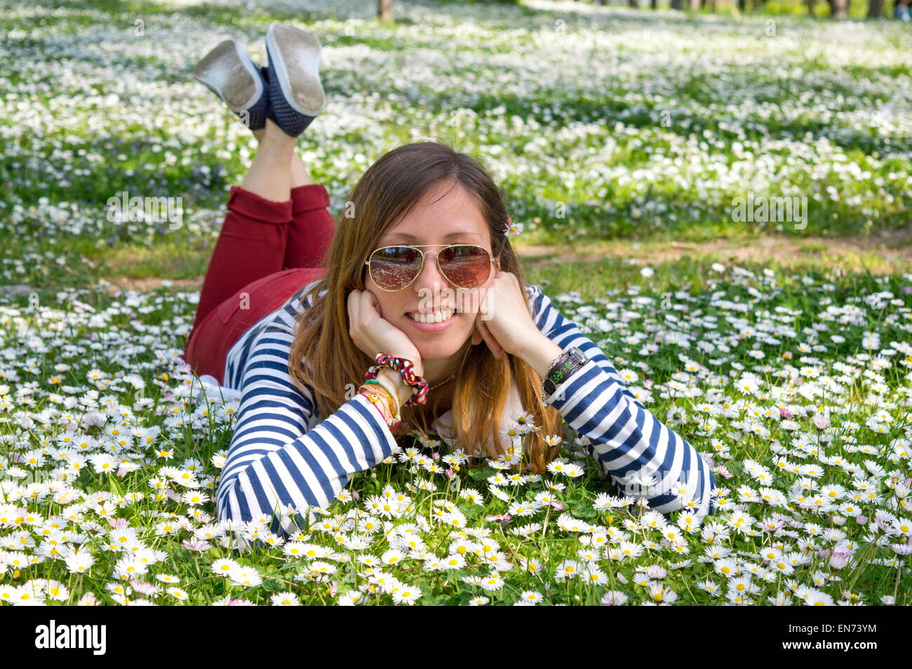 Bruna ragazza distesa in erba pieno di fiori Foto Stock