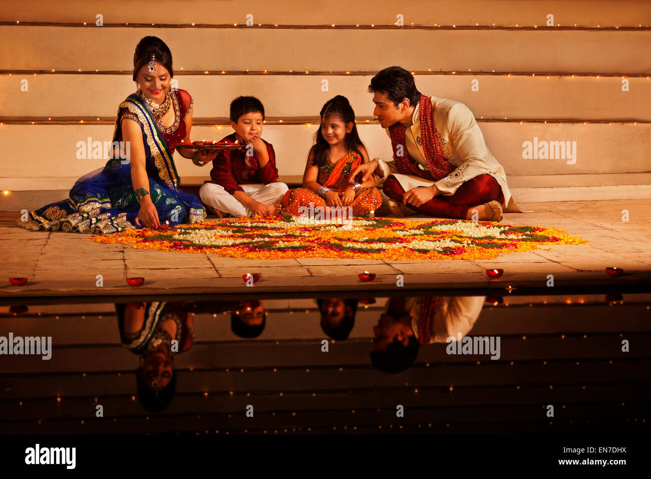 Famiglia disponendo diyas su rangoli Foto Stock