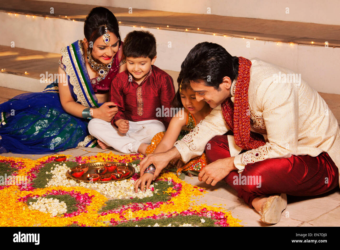 Famiglia disponendo diyas su rangoli Foto Stock