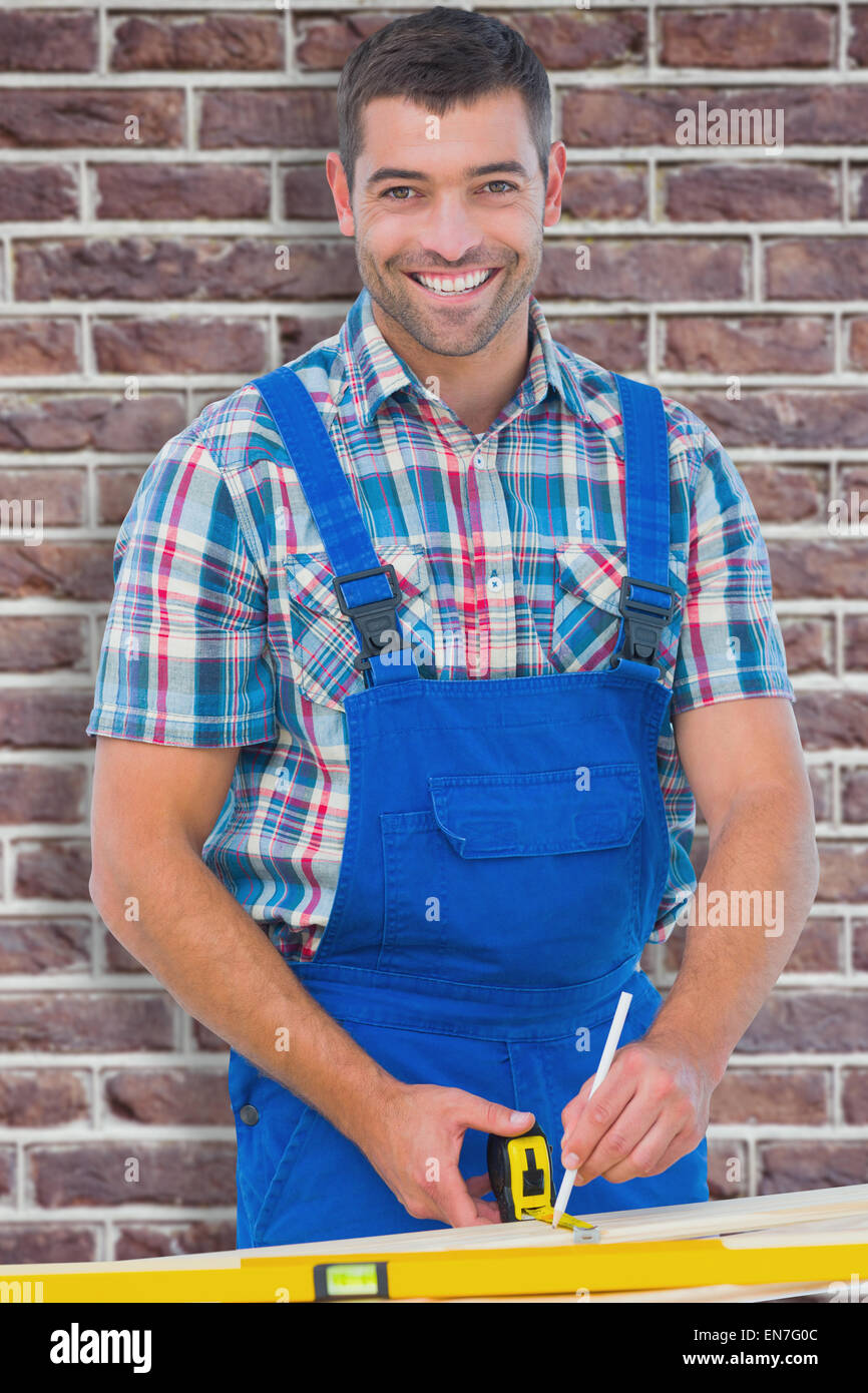 Immagine composita di fiduciosa carpenter marcatura sul listone con nastro di misurazione Foto Stock