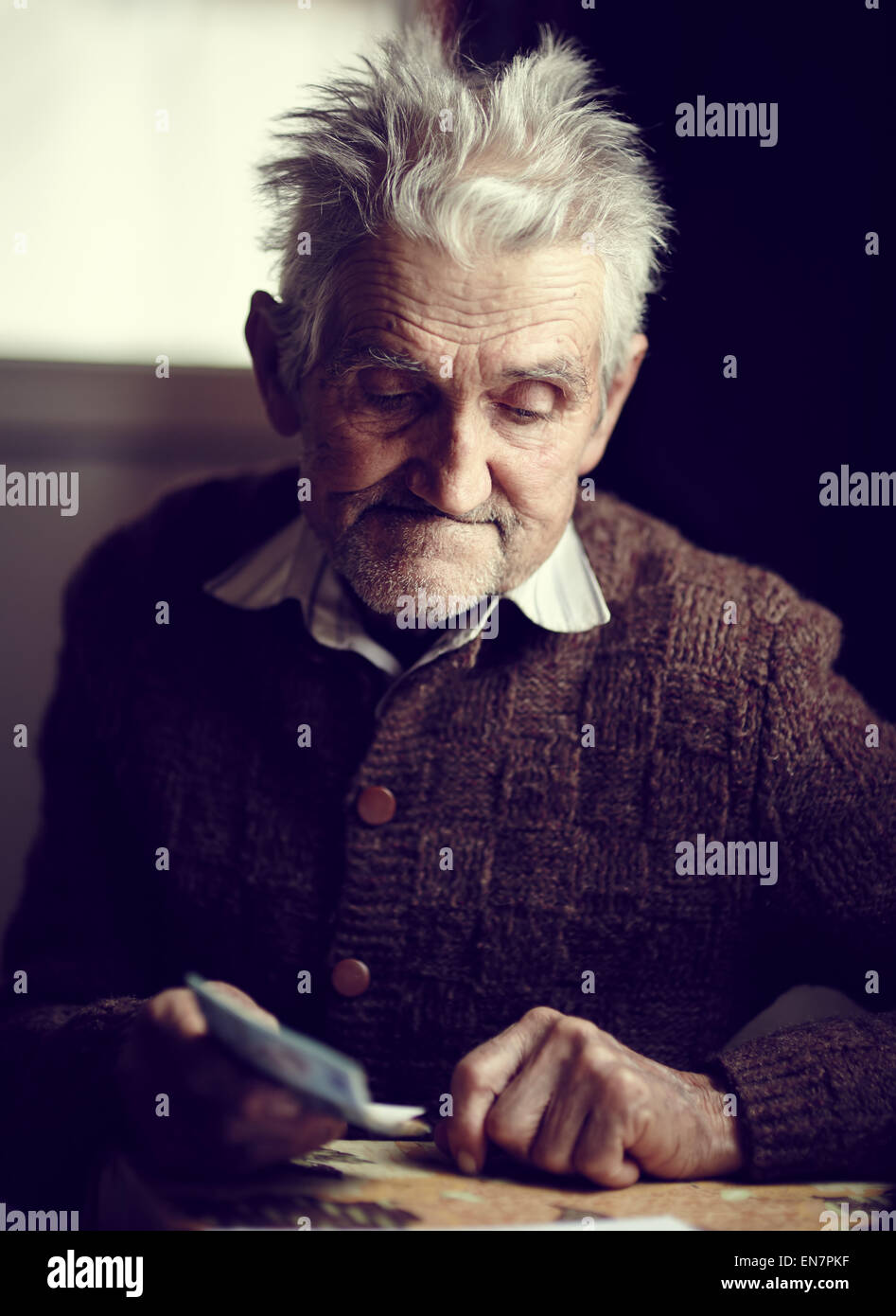 Il vecchio uomo nella sua 80s avendo appena ricevuto la sua piccola pensione, con un pensieroso espressione sul suo volto Foto Stock