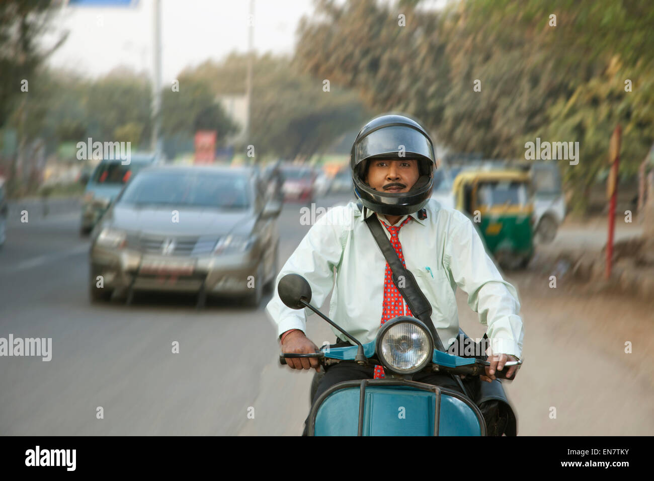 Venditore scooter di equitazione nel traffico, sorridente Foto Stock