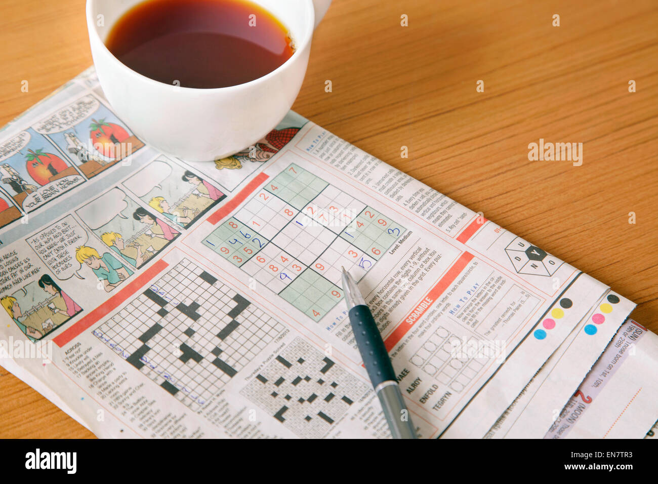 Il caffè con il giornale il cruciverba Foto Stock