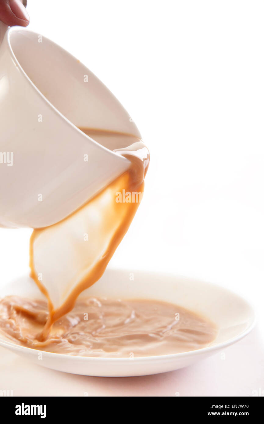 Il tè versando in piattino isolati su sfondo bianco Foto Stock