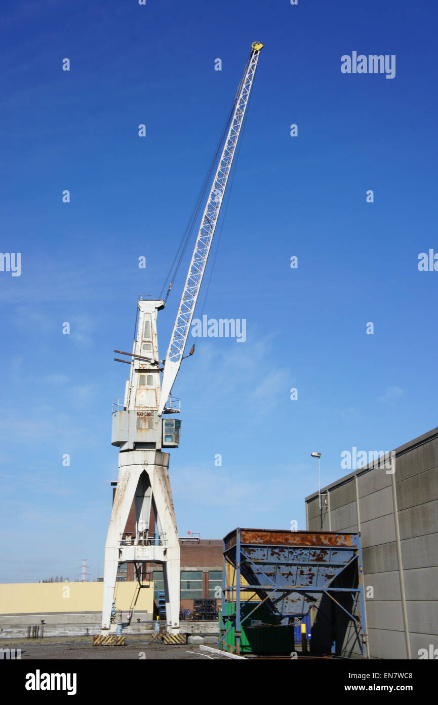 Questa foto cattura una vecchia gru portuale situata a Wilmarsdonksteenweg nel porto di Anversa. La gru è un elemento fondamentale dell'infrastruttura utilizzata per caricare e scaricare merci nel porto affollato. Foto Stock