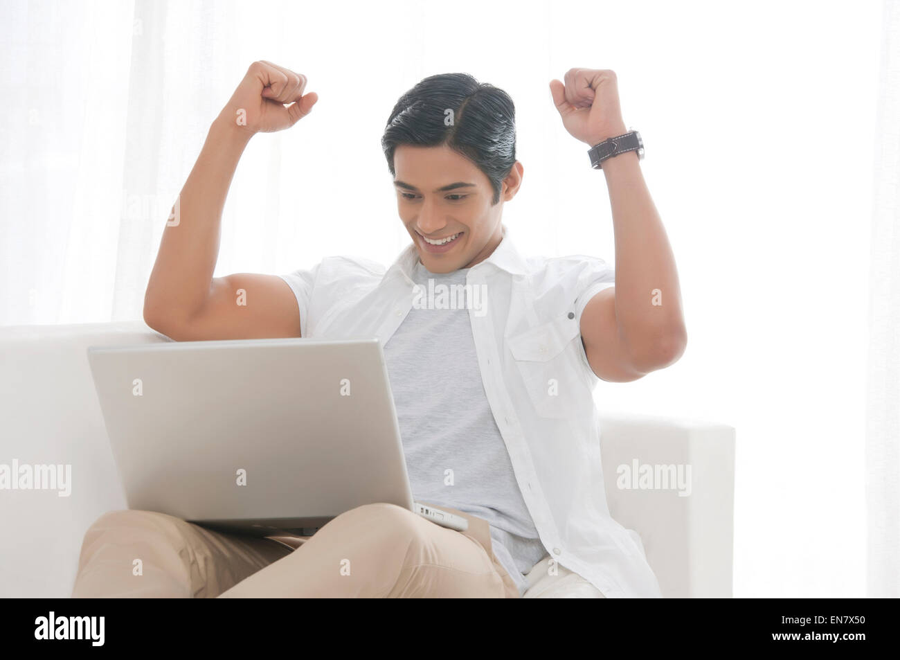 Giovane uomo con gioia per laptop Foto Stock