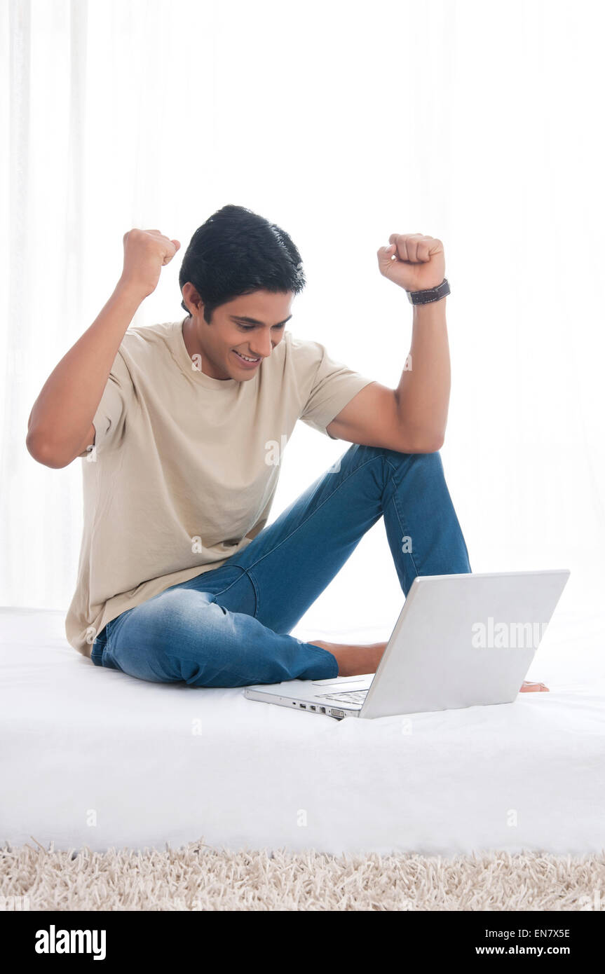 Giovane uomo con gioia per laptop Foto Stock