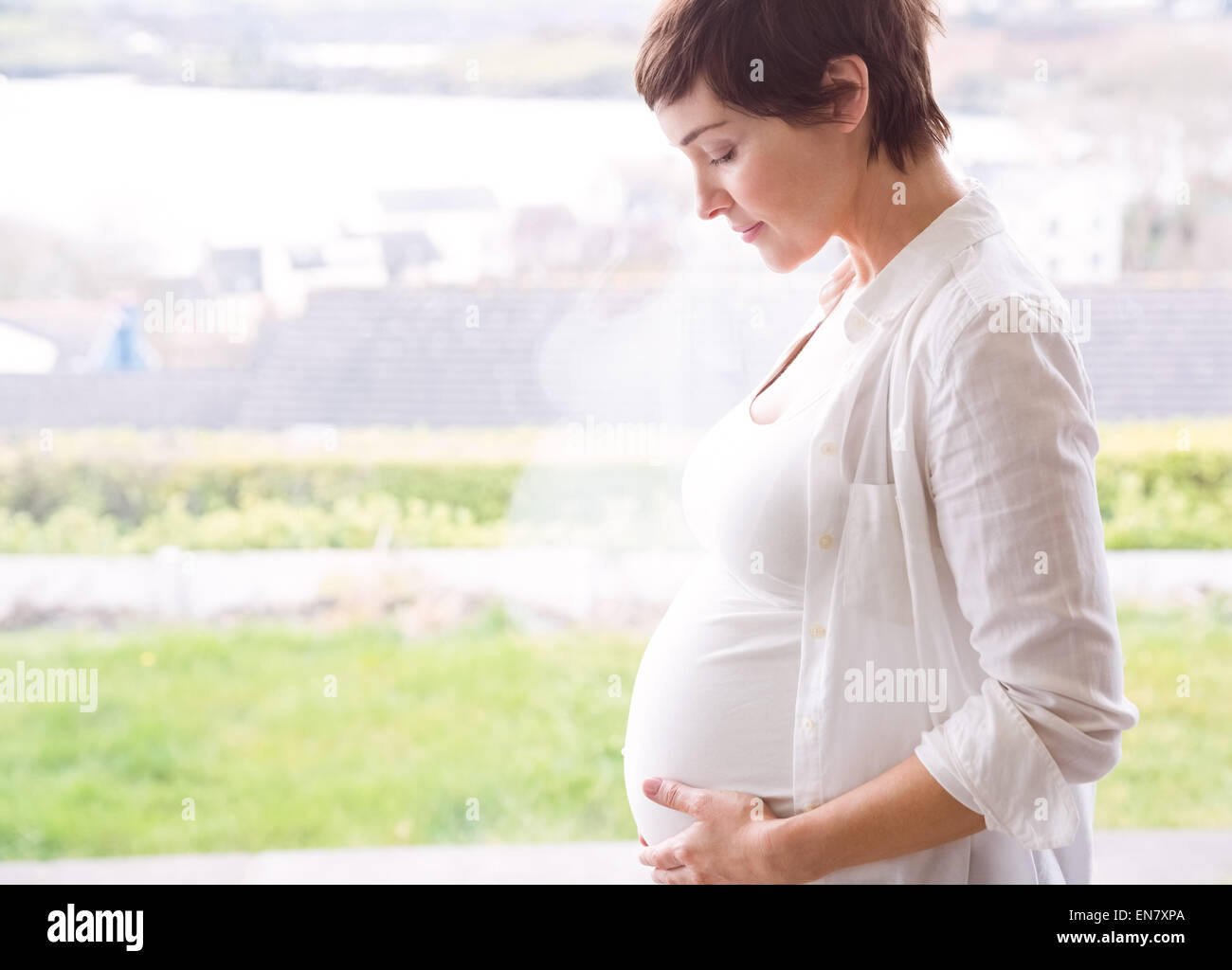 Donna incinta mentre tiene il suo bump Foto Stock