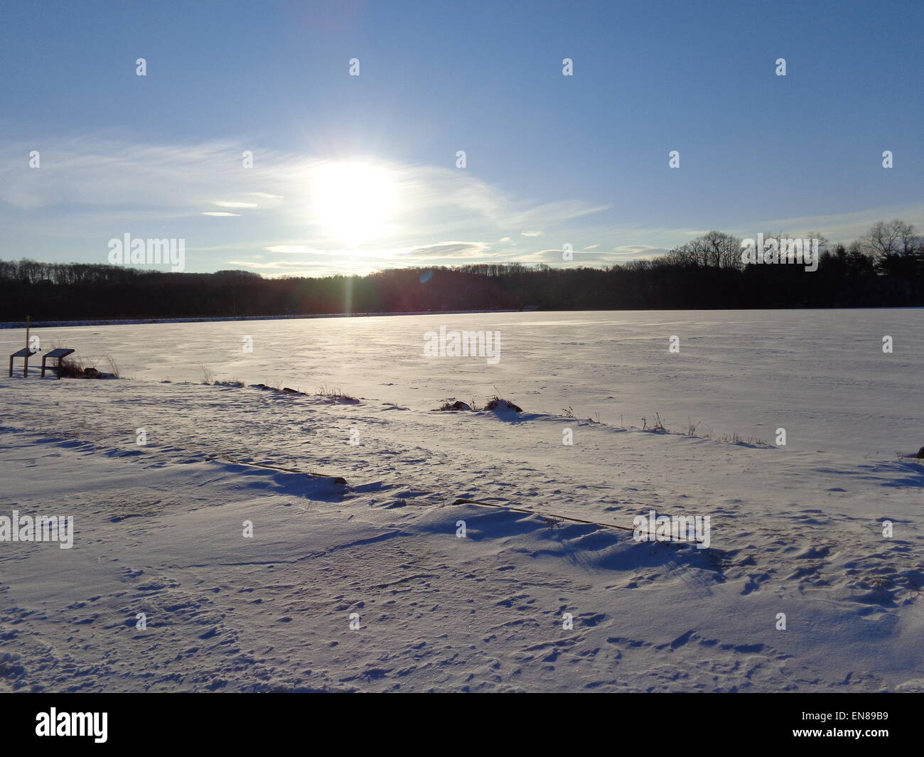Sun andando verso il basso e riflettendo su un lago congelato di ghiaccio e neve. Foto Stock