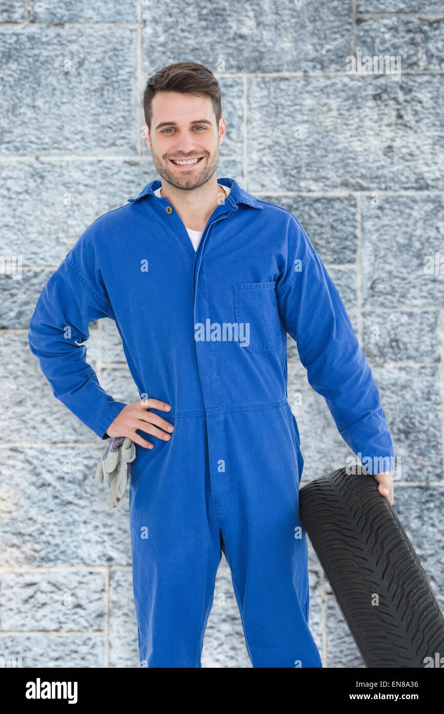 Immagine composita di sorridere meccanico maschio di contenimento del pneumatico Foto Stock