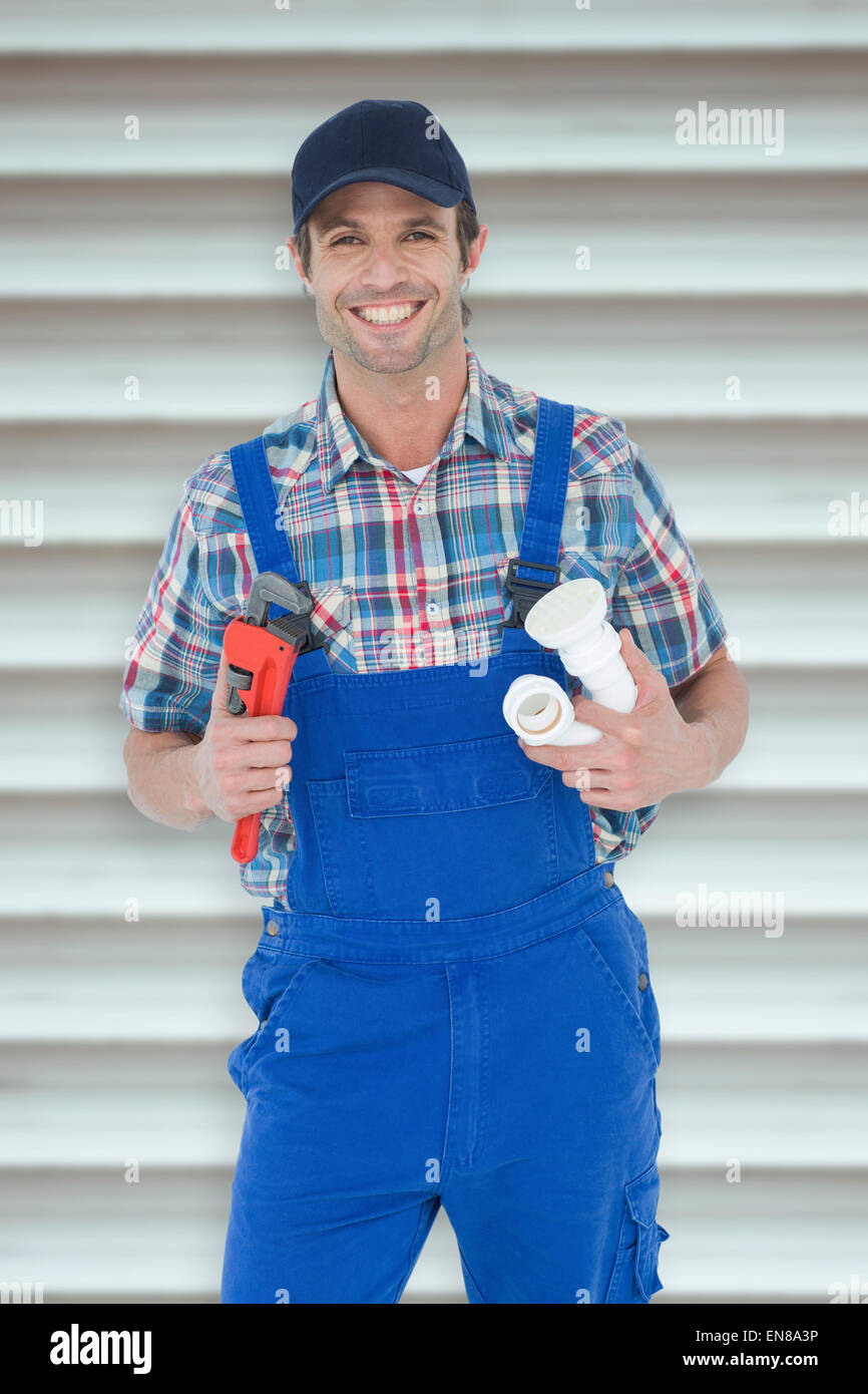 Immagine composita di plumber holding Monkey Wrench e tubo dissipatore Foto Stock