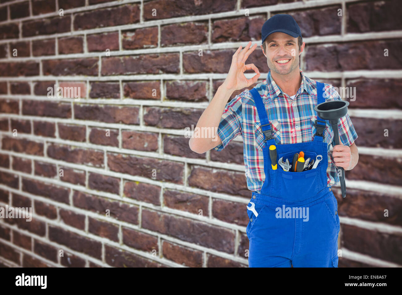 Immagine composita di plumber tenendo premuto lo stantuffo mentre gesti segno ok Foto Stock