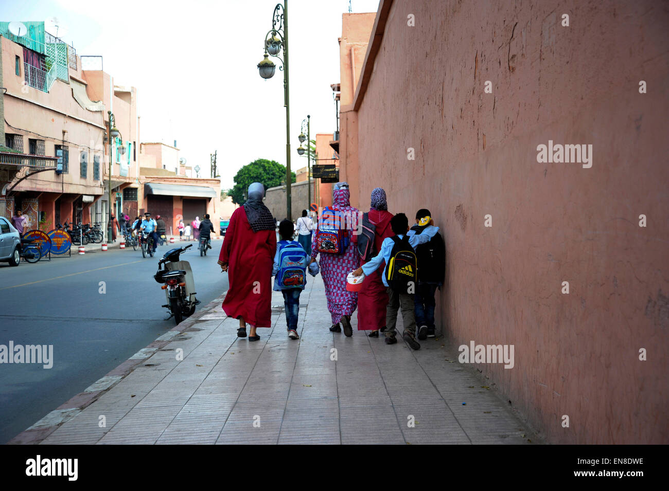 Famiglia di ritorno da scuola a scuola correre lungo una strada principale in marrakech Africa del nord Foto Stock